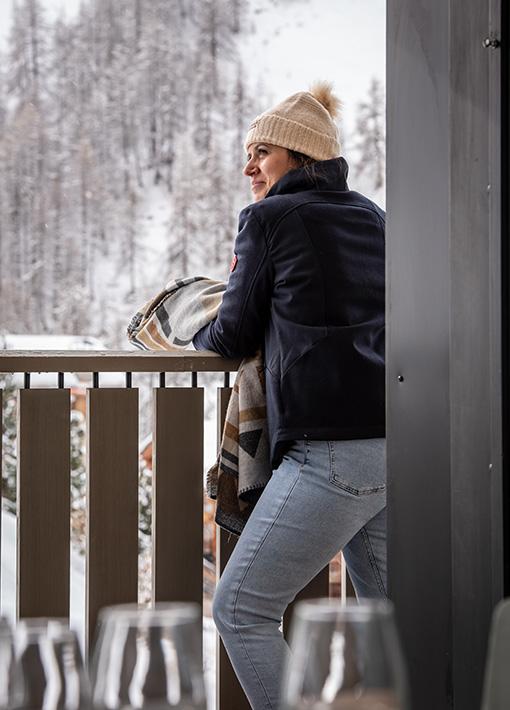 Jeune femme sur un balcon vue pistes des chalets Izia à Val d'Isère